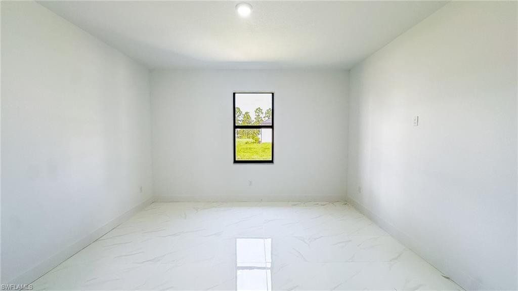 White walls with a single window featuring a black frame and a flush-mount ceiling light