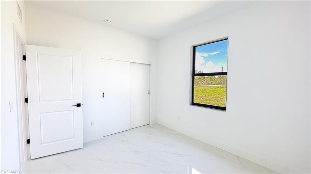Bright interior with white walls, window, white paneled door with black hardware, and white sliding closet doors