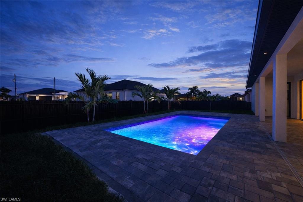 Pool at dusk with a patio area and a fenced backyard