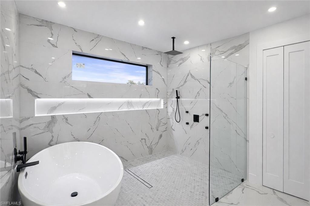 Full bathroom with stone wall, a marble finish shower, a soaking tub, recessed lighting, and marble finish floors