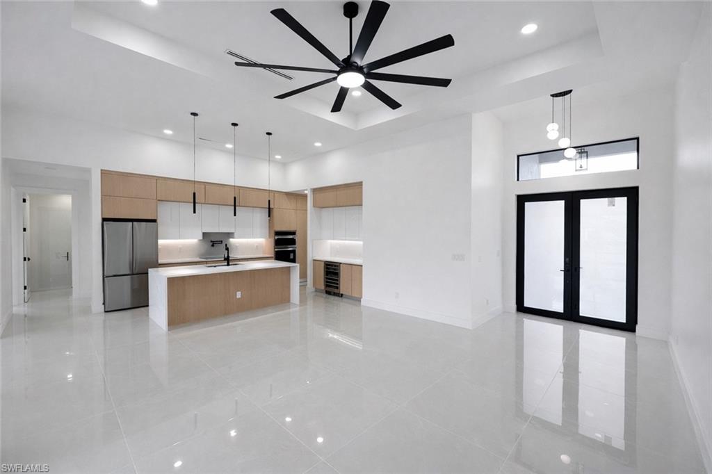 Kitchen with a spacious island, decorative light fixtures, a tray ceiling, freestanding refrigerator, and wine cooler