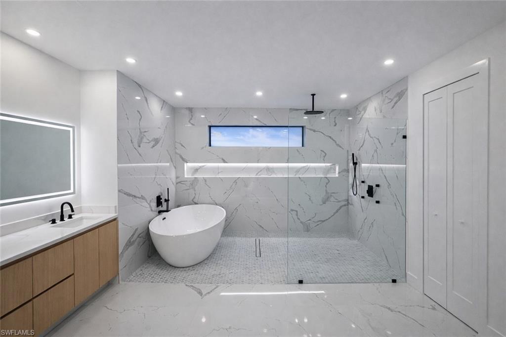 Full bath featuring a marble finish shower, vanity, recessed lighting, a freestanding tub, and light marble finish floors