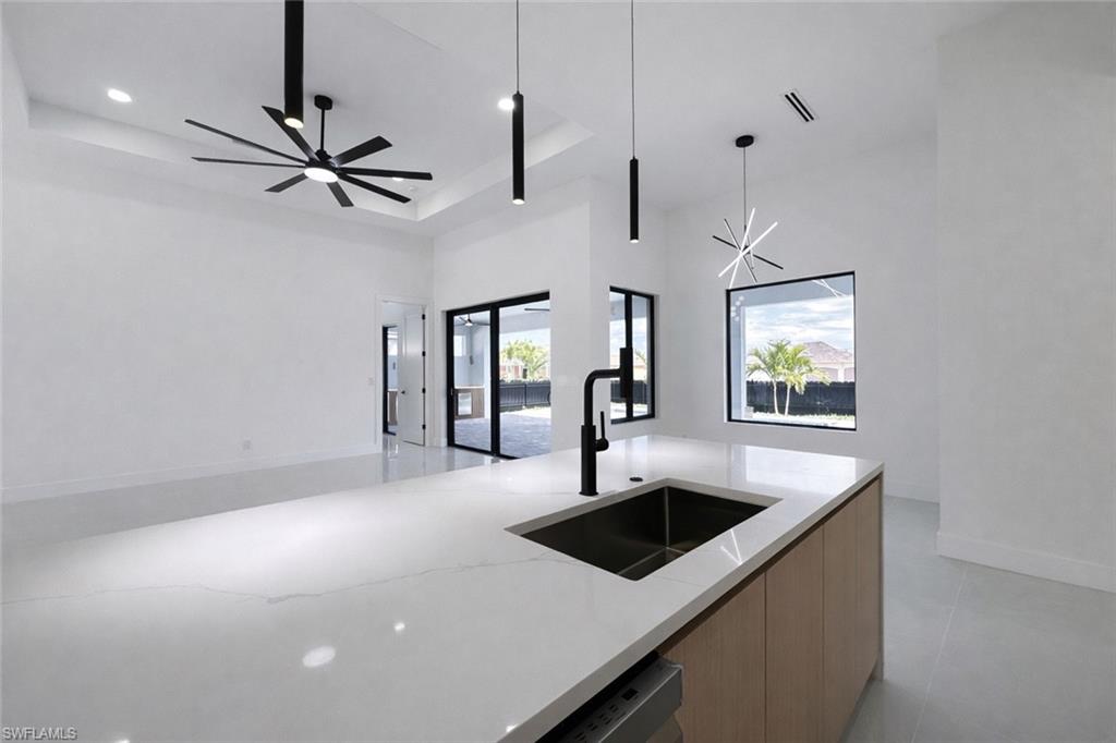 Kitchen featuring modern cabinets, light stone countertops, a raised ceiling, suspended lighting, and open floor plan