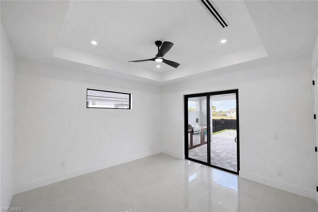 Spare room with ceiling fan, recessed lighting, light tile patterned floors, and a tray ceiling