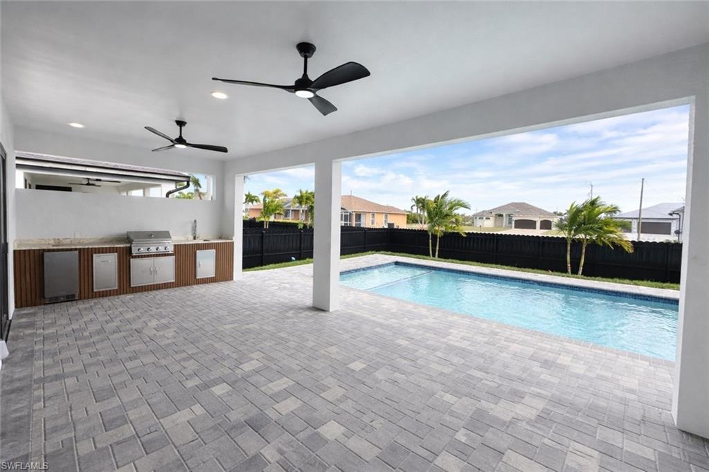 View of swimming pool with an outdoor kitchen, patio surround, a fenced backyard, and a residential view