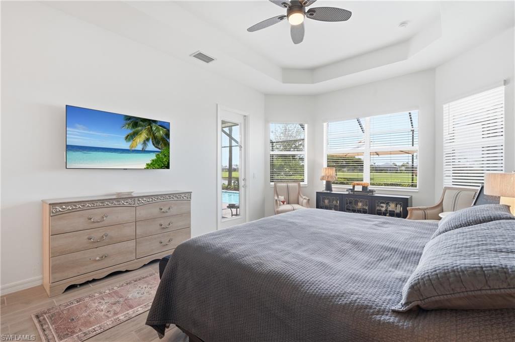 Primary bedroom with tray ceiling, door to lanai and bay window