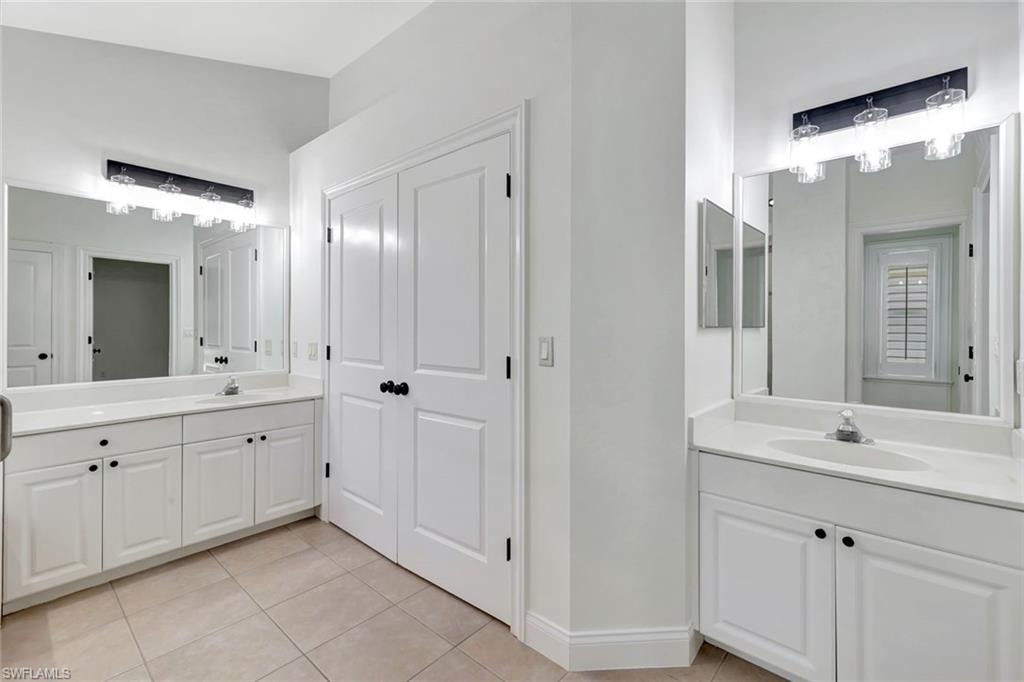 Dual vanities with integrated sinks, white cabinetry, and matte black hardware