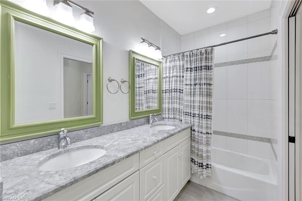 Dual vanity with an undermount sink, a stone countertop, and decorative framed mirrors