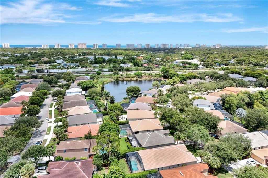 Expansive residential area featuring a prominent body of water, extensive tree canopy, and distant coastal structures