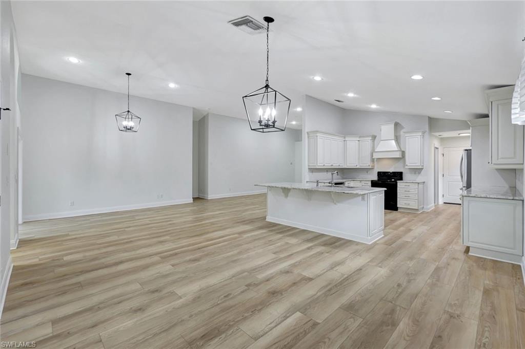 Open-concept living space featuring wood-finish flooring, recessed lighting, and two geometric pendant lights