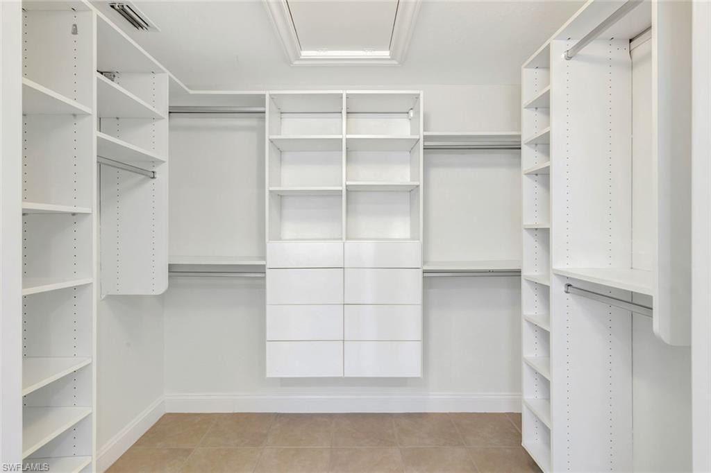 Custom closet system featuring extensive shelving, multiple hanging rods, integrated drawers, and a skylight