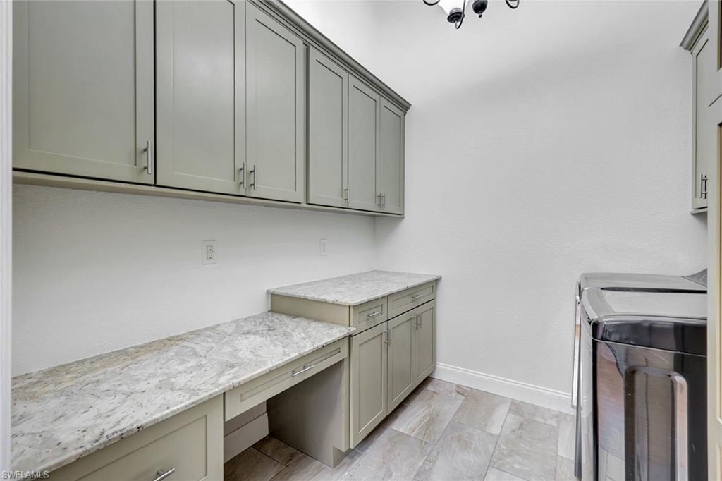 Cabinetry with light gray finish, granite-style countertops, integrated desk area, and tile flooring