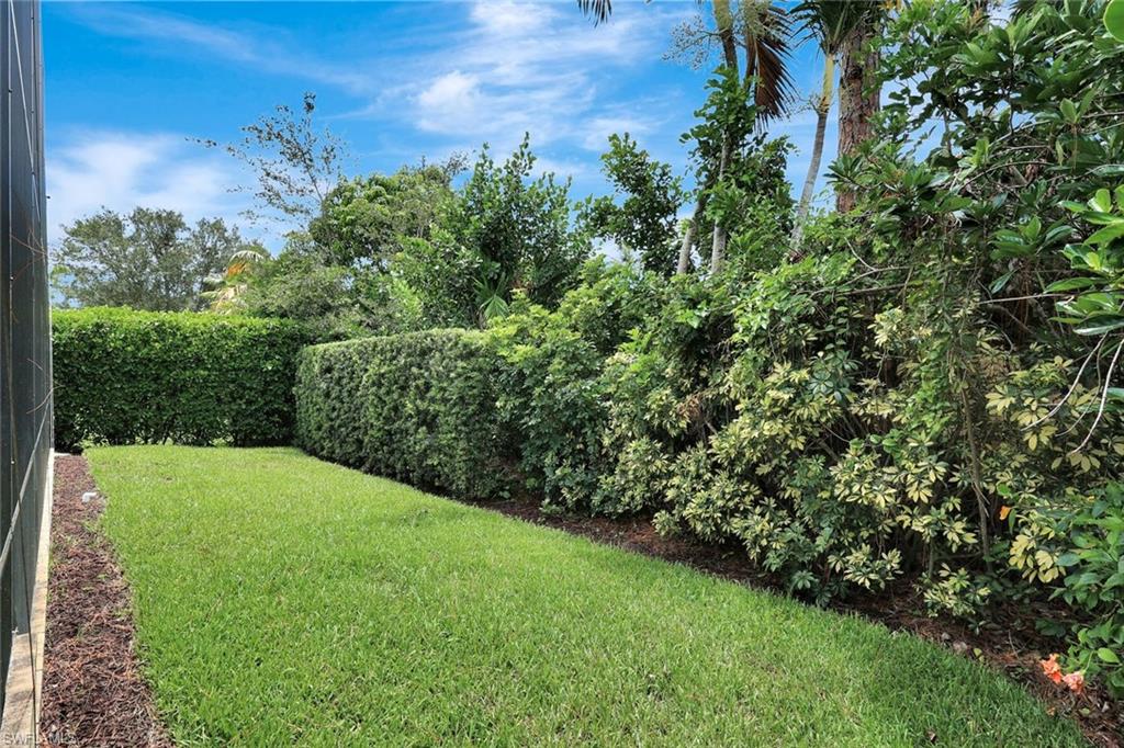 Expansive green lawn with established hedge-lined perimeters and a privacy screen