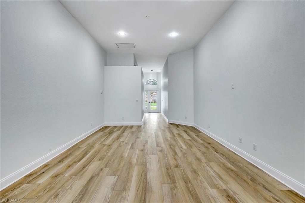 Recessed lighting illuminates wood-finish flooring and pristine white walls
