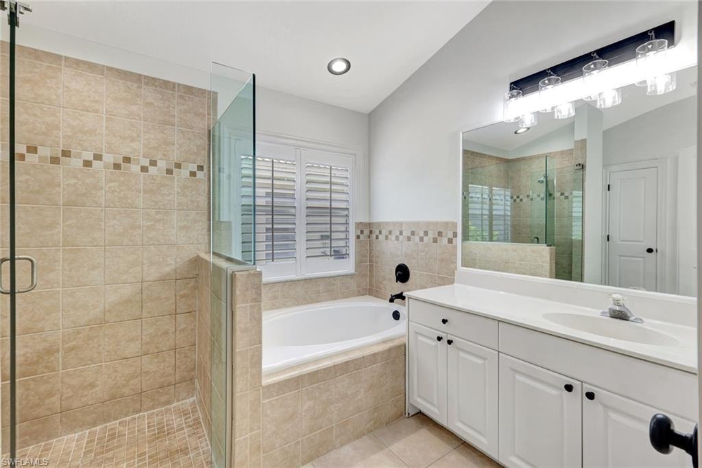 Spacious bathroom with a walk-in shower, built-in soaking tub, dual-sink vanity, and white plantation shutters
