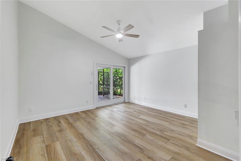 Vaulted ceiling, wood-finish flooring, ceiling fan, and white sliding glass doors