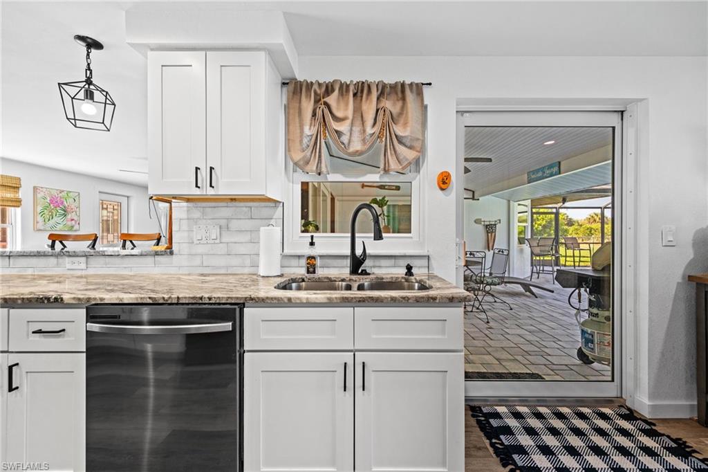 White shaker-style cabinetry with matte black hardware, stone-finish countertops, subway tile backsplash, and a built-in dishwasher