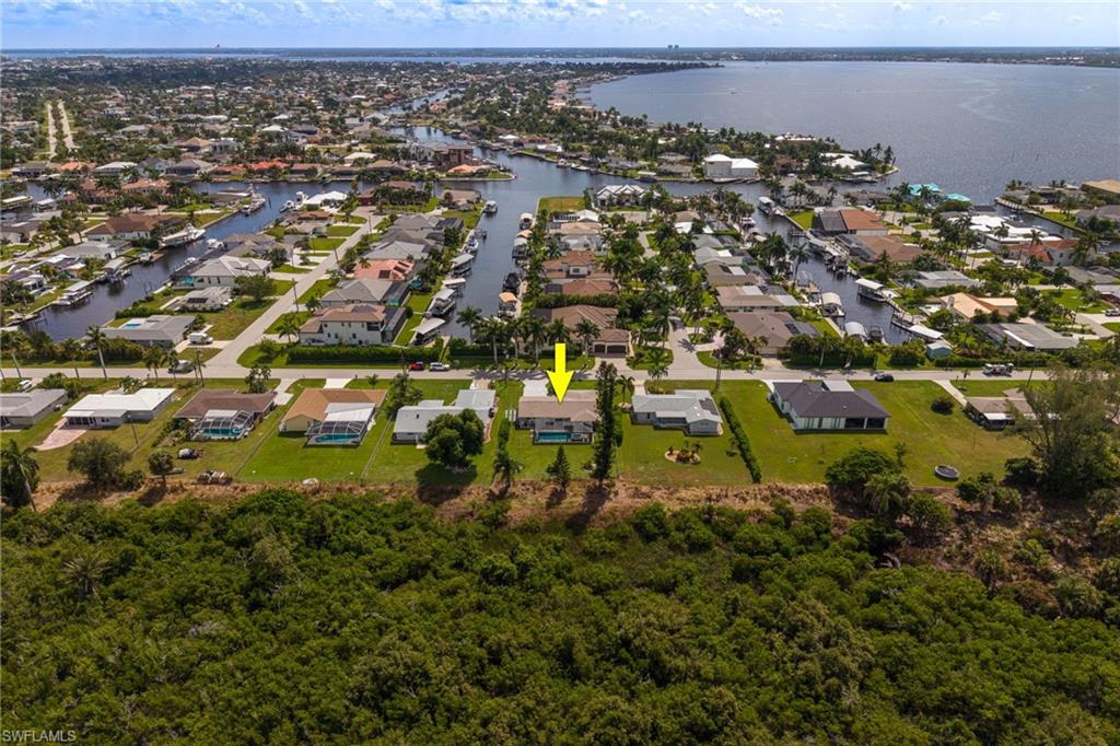 Aerial perspective showcasing a residential area with canal access, waterfront properties, and a large body of water in the background