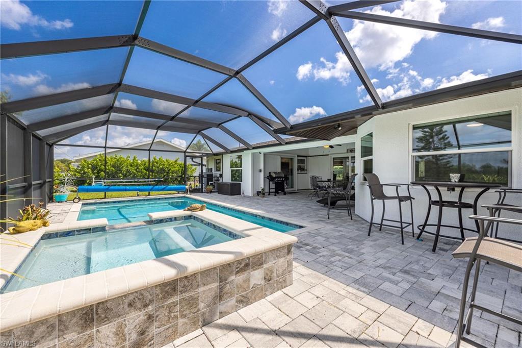 Screened outdoor living space featuring a pool, spa, and paver patio