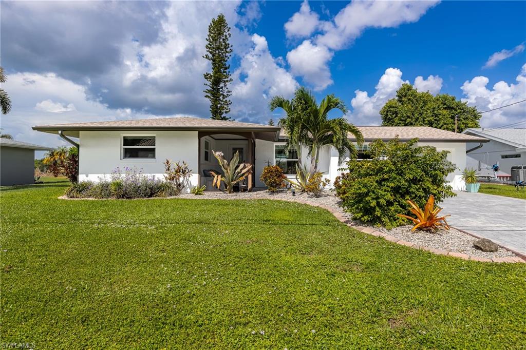 White exterior, light-toned shingle roof, established landscaping, concrete driveway, and covered entry