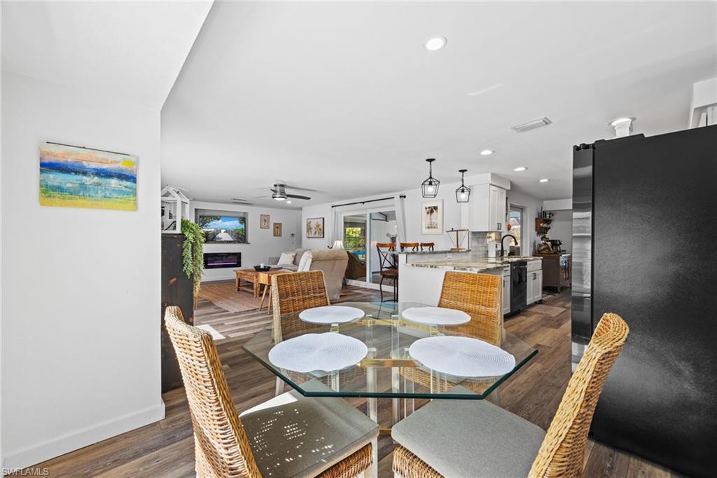 Open-concept interior featuring wood-finish flooring, recessed lighting, and a kitchen with white cabinetry and a built-in refrigerator