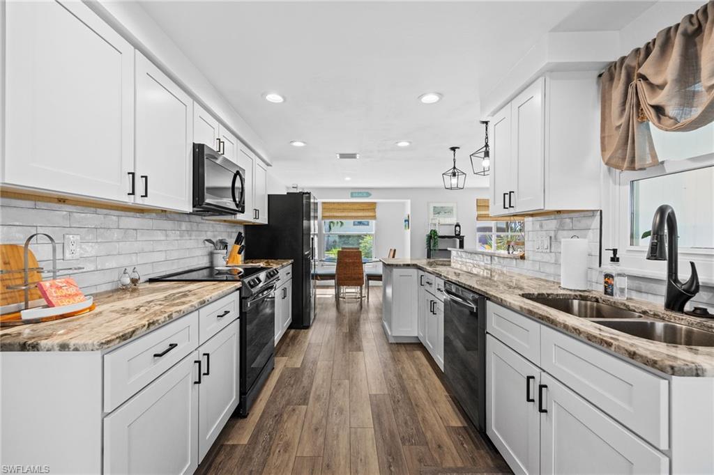 Galley kitchen featuring wood-finish flooring, white cabinetry, dark stone countertops, a subway tile backsplash, and recessed lighting