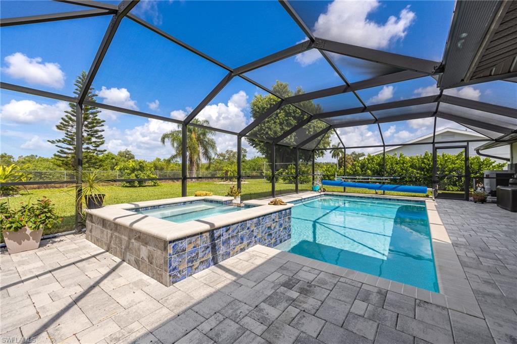 Screened lanai featuring a swimming pool, integrated spa with mosaic tile, and paver decking