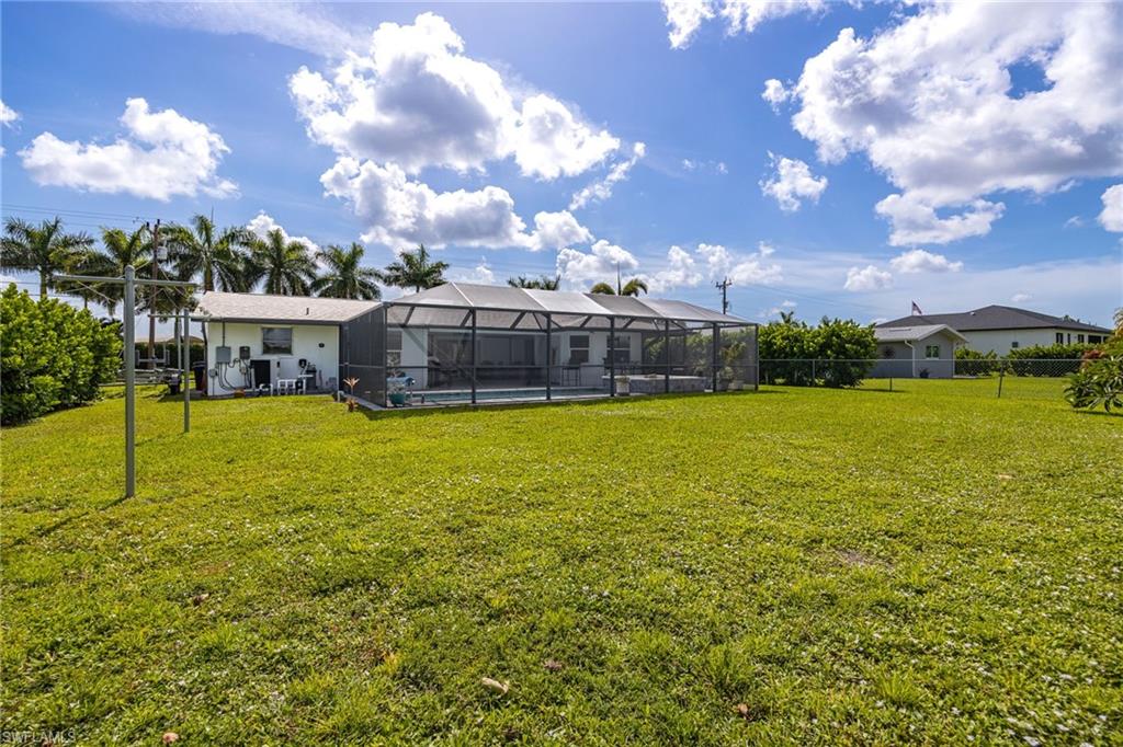 Expansive green lawn with a screened-in swimming pool and mature palm trees