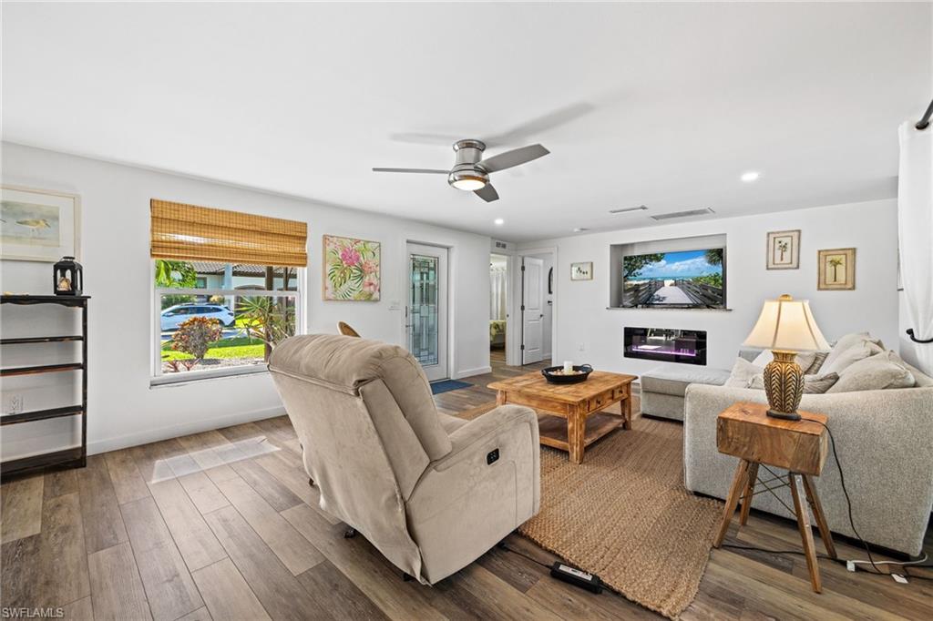 Wood-finish flooring, recessed lighting, and a ceiling fan enhance this living space
