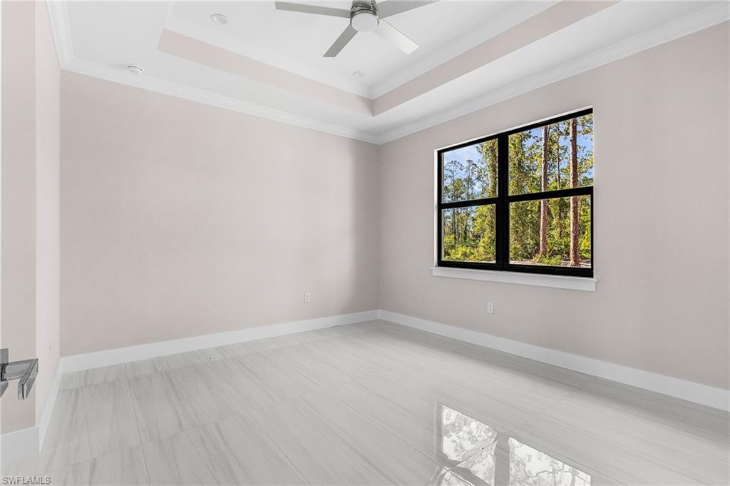 Tray ceiling, recessed lighting, ceiling fan, large window with black frame, and wood-finish flooring