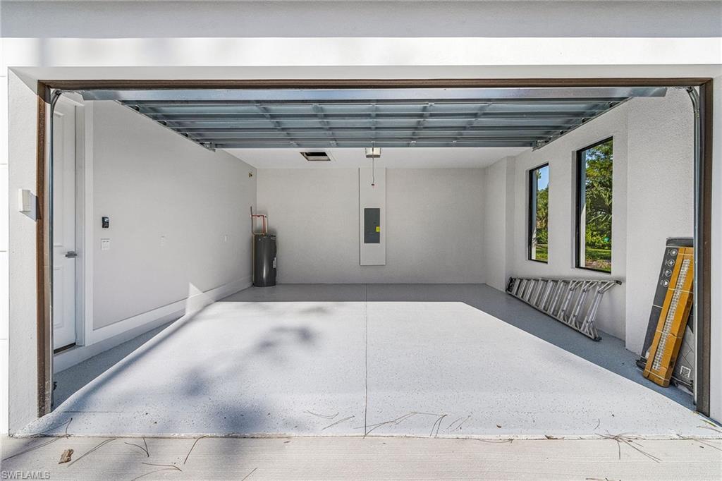 Spacious garage with light grey epoxy flooring, recessed lighting, and two vertical windows