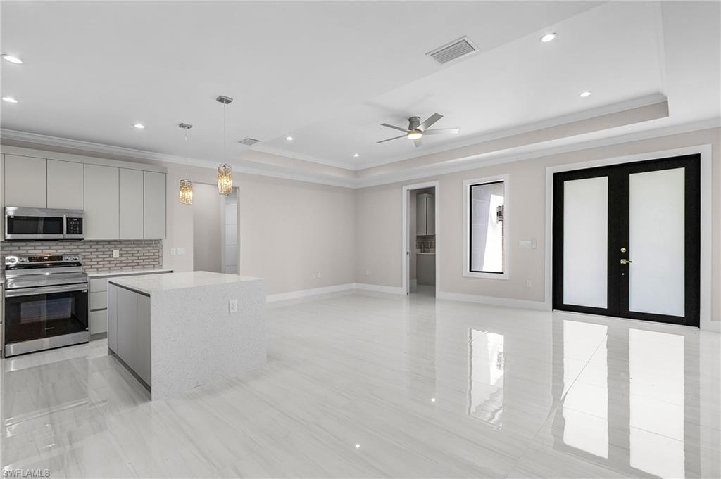 Open-concept living area featuring a kitchen island with stone countertop, stainless steel appliances, recessed lighting, and large format tile flooring