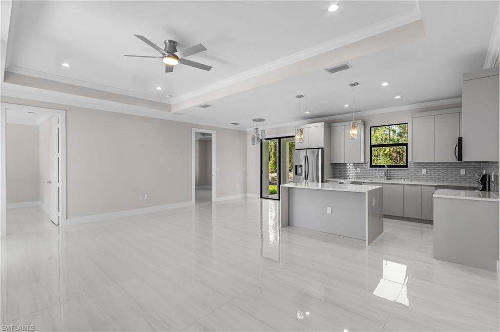 Open-concept living space with large format tile flooring, a tray ceiling, and recessed lighting