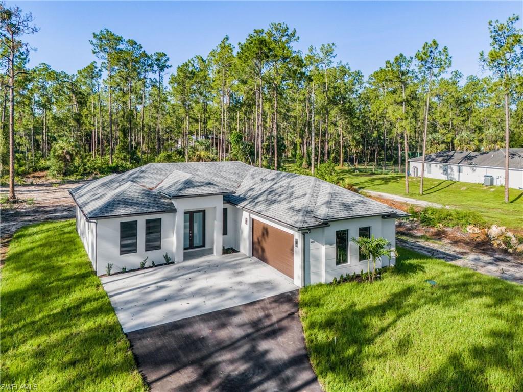 Contemporary white exterior with a gray shingle roof, two-car garage with a wood-finish door, concrete driveway, and front landscaping