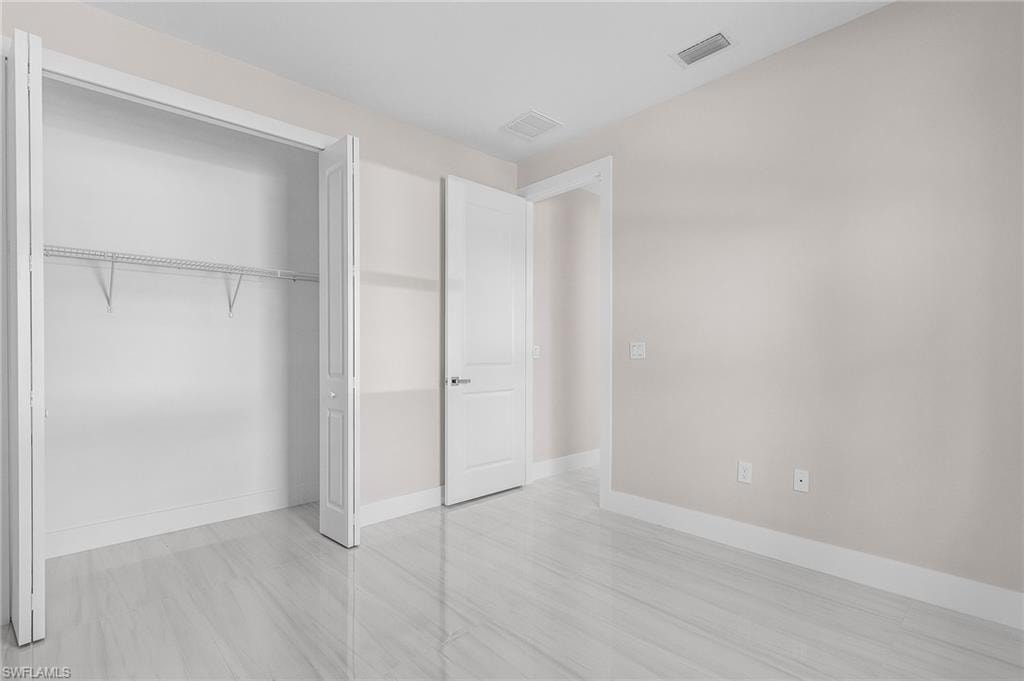 White bi-fold closet doors with wire shelving, light wood-finish flooring, white trim, and a white interior door