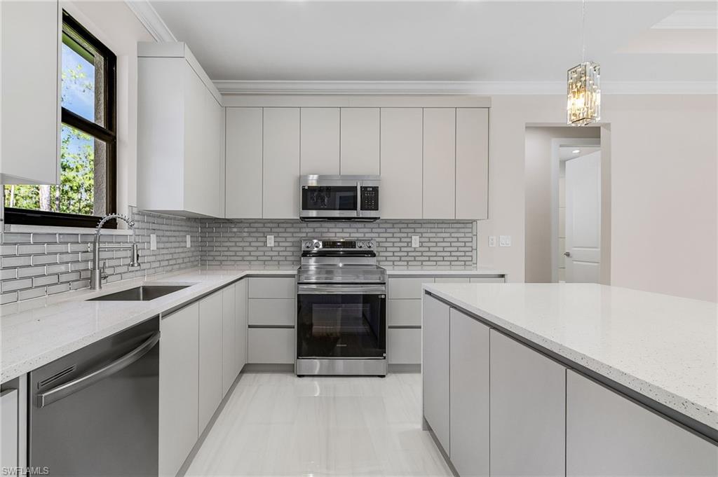 Contemporary kitchen featuring a large island, stainless steel appliances, light cabinetry, and a subway tile backsplash