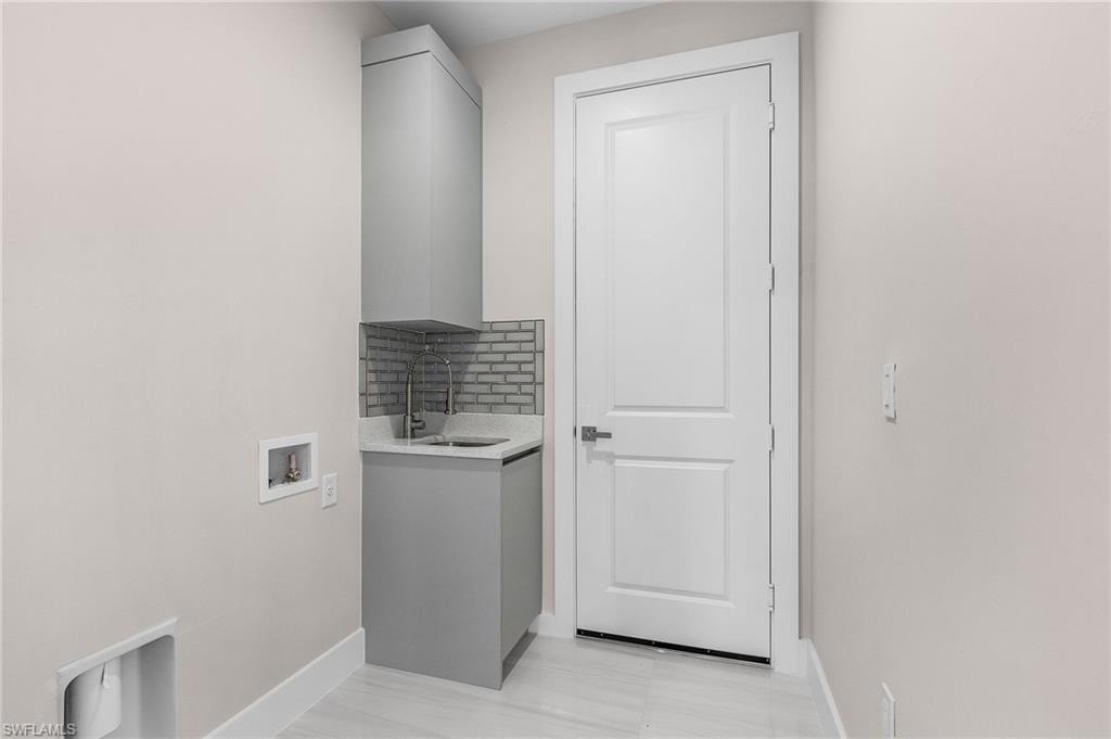 Built-in sink with wall-mounted faucet, subway tile backsplash, and light-toned cabinetry