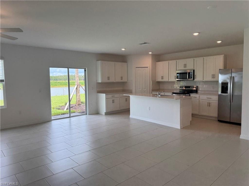 Kitchen with white cabinetry, stainless steel appliances, and an island