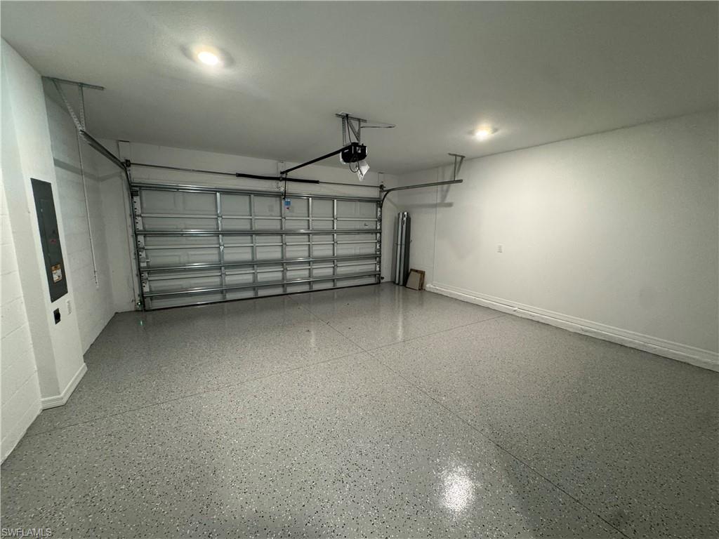 Spacious garage featuring a durable epoxy floor finish, automatic garage door opener, and recessed ceiling lighting