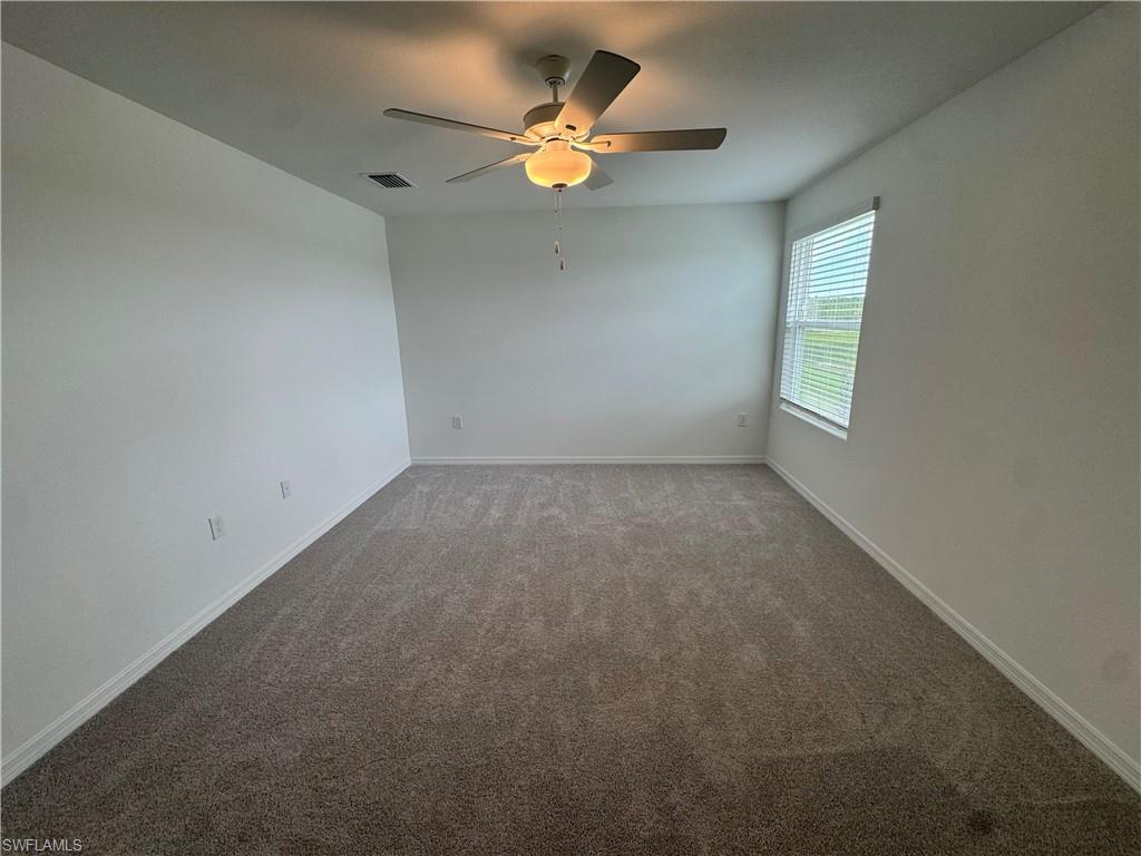 Recessed window with horizontal blinds, neutral wall paint, ceiling fan with integrated lighting, and neutral tone carpeting