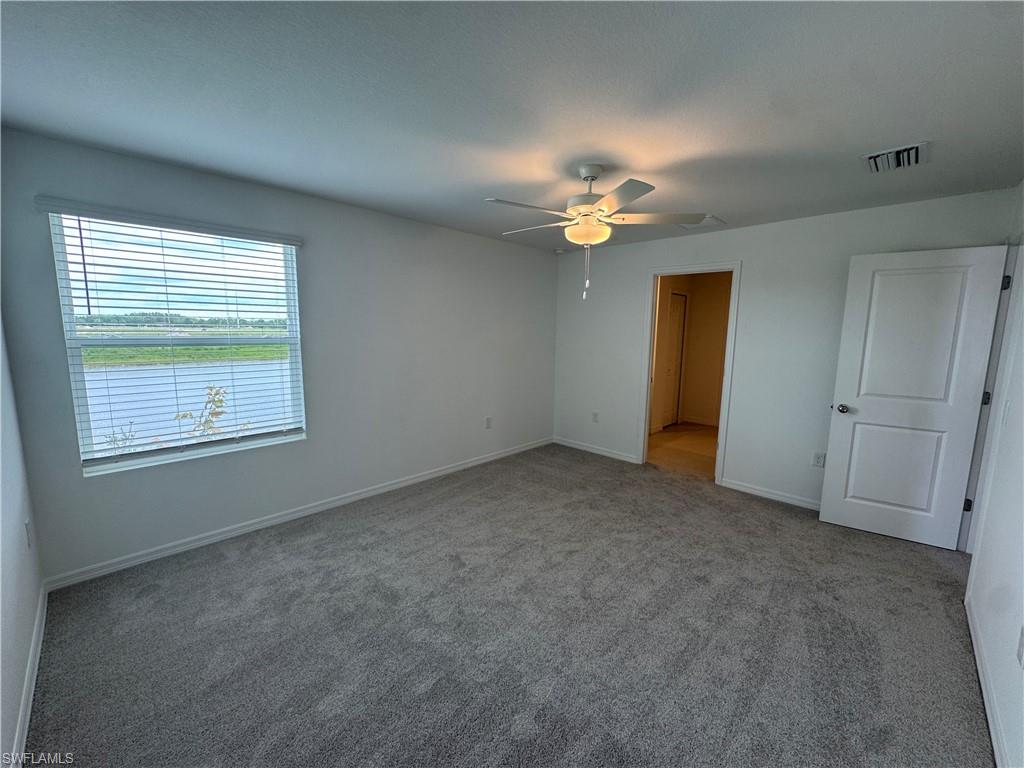 Carpeted flooring, white walls, ceiling fan, window with horizontal blinds, and a white interior door