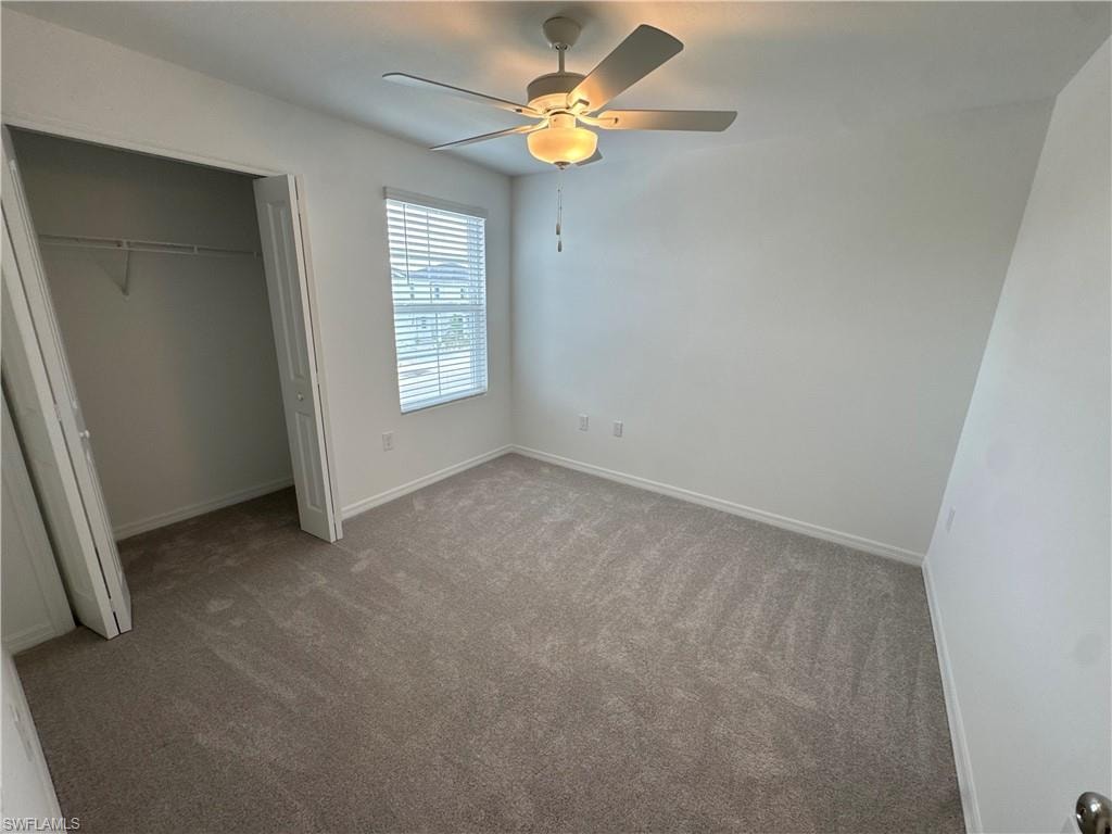 Neutral tone wall finishes, gray carpet, ceiling fan with integrated lighting, window with blinds, and a bi-fold closet