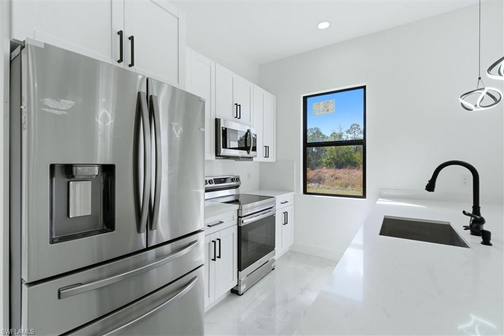 Kitchen featuring stainless steel appliances, white cabinetry with black hardware, white countertops, and a black faucet