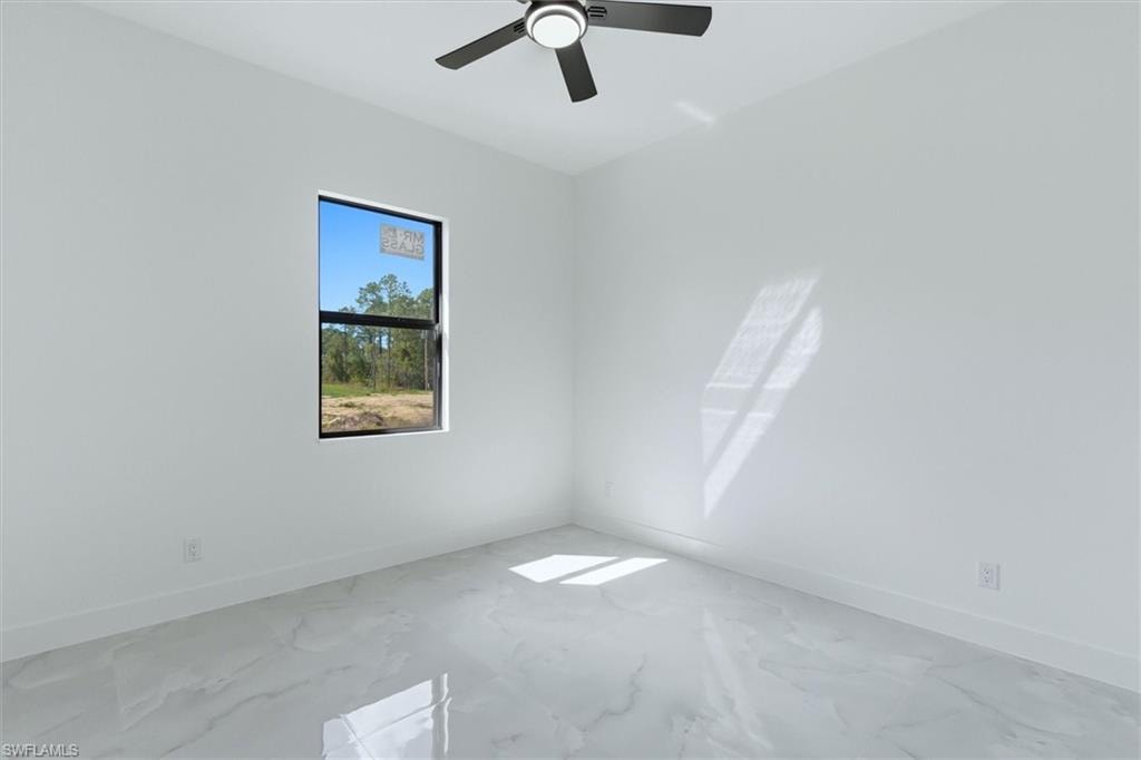 White walls, large window, white baseboards, tile flooring, ceiling fan