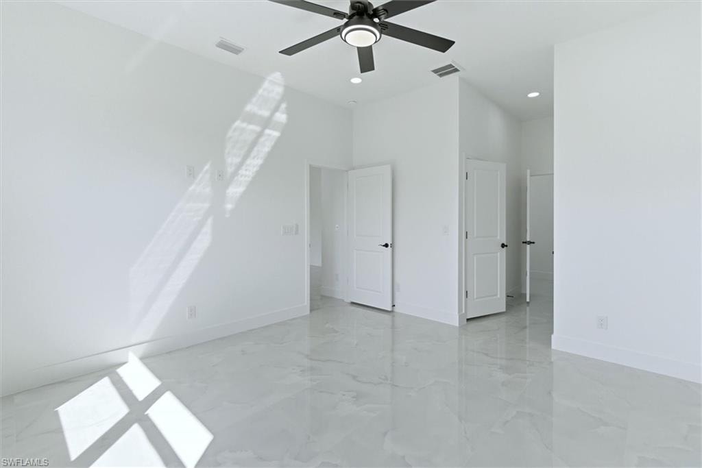 Glossy tile flooring, white walls, black ceiling fan with integrated lighting, recessed lighting, and white doors with dark hardware