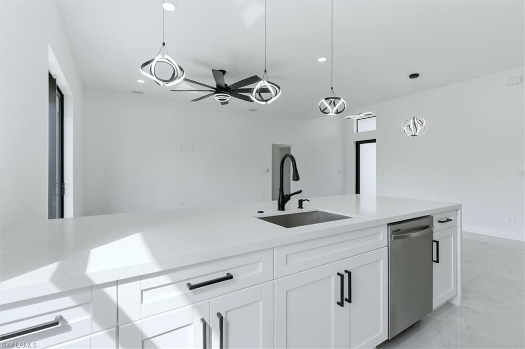 Kitchen island with white cabinetry, stainless steel sink, and integrated dishwasher
