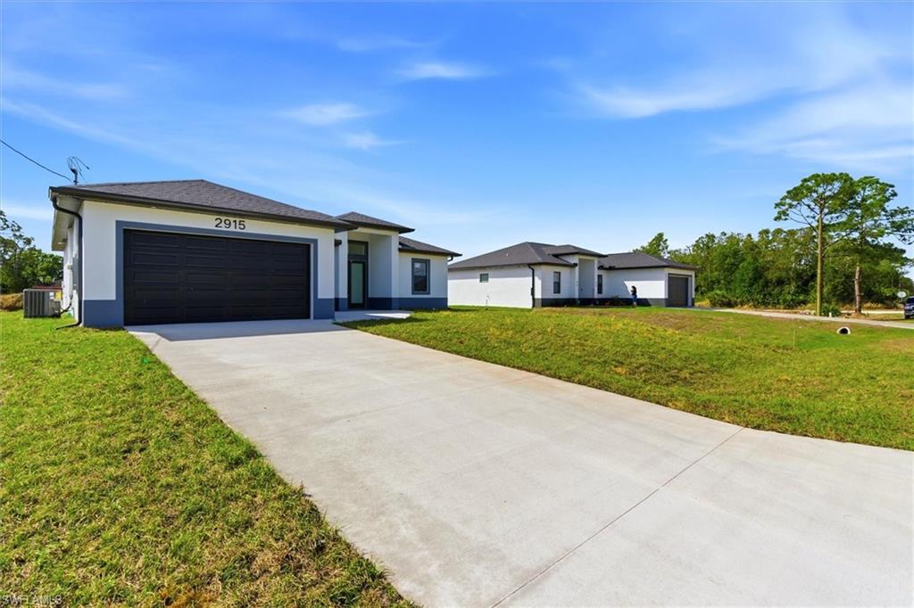 Contemporary stucco exterior with a dark-finish garage door, concrete driveway, and a well-maintained lawn
