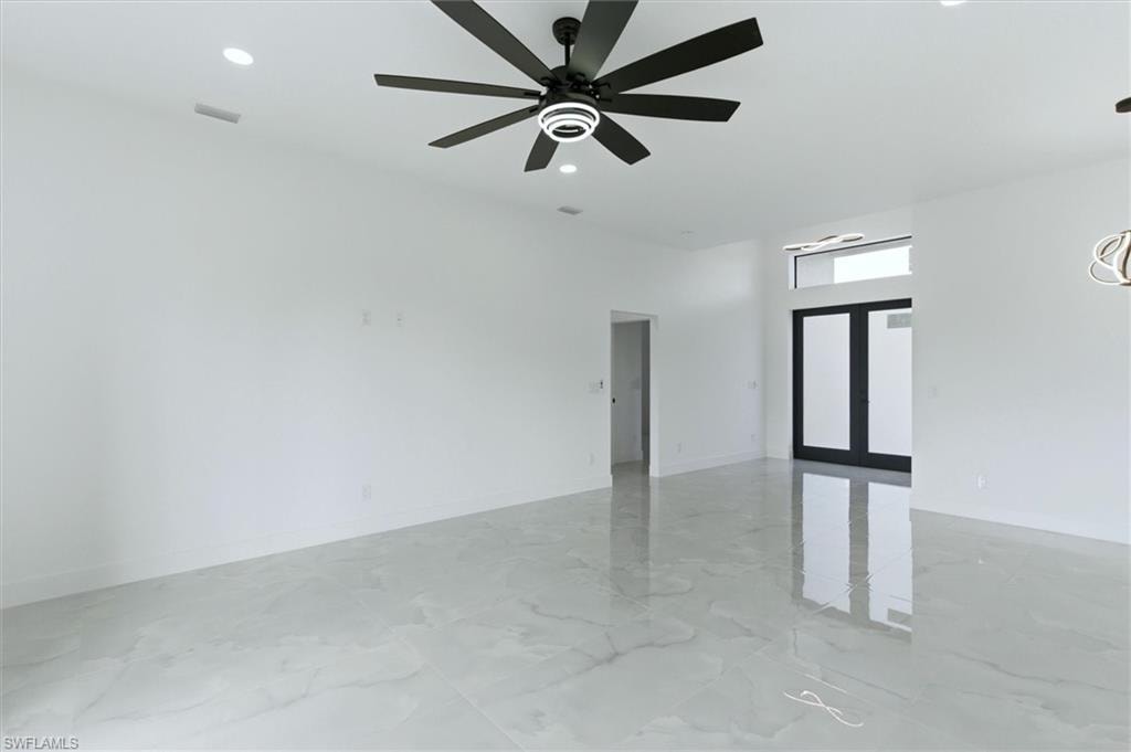 Spacious room featuring large format tile flooring, a modern black ceiling fan, recessed lighting, and a prominent entry door with an overhead transom window