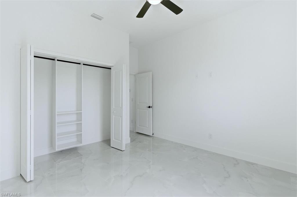 White walls, tile flooring, built-in closet shelving, and a ceiling fan