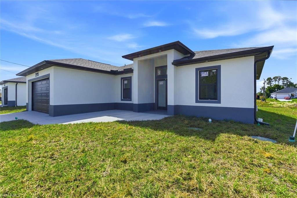 Modern stucco exterior with dark trim accents, covered entry, and attached garage